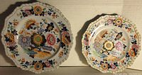 Top view photo showing two Ridgeway stoneware plates with detailed multi-color floral decorations and scalloped edges.