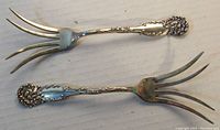 Pair of two sterling silver serving forks showing the full length and splayed fork tines.