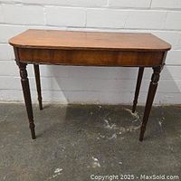 Front view showing the whole antique console table with turned legs and flamed mahogany apron.