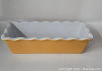 Side view of the loaf pan showing orange exterior and white interior with fluted edge.