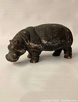 Side view of hand-painted hippopotamus figurine showcasing wear, chips on feet and textured finish.