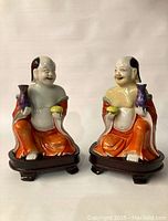 Front view of both figurines side by side showing facial expressions, robes and accessories.