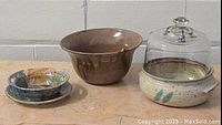 All three pottery pieces shown together with soda can for scale: cream lidded pot with glass dome, brown bowl, decorative bowl with plate