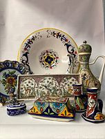Overview of the collection showing all nine ceramic and faience pieces arranged together revealing colors, shapes, and designs.