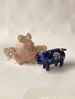 Full view of both objects, showing the cloisonné pig figurine beside the rose quartz carved piece.