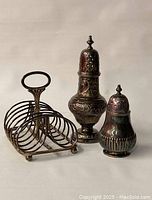 Photo of silver plated toast rack and two sugar castors showing overall vintage condition and design of each item