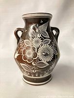 Front view of the vintage Mexican pottery vase showing detailed white floral patterns on a red-brown burnished clay body with double handles.