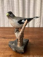 Front-left angle view of the bird model and base, showing the natural stone base and faux branch detail.