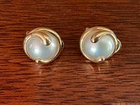 Top view of both earrings showing swirl gold settings and white pearls