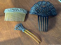 Full view of all three celluloid hair combs laid out on wooden surface showing size and design variety.