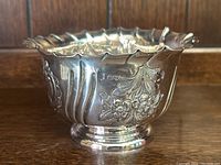 Full side profile view of footed silver bowl showing crimped rim and floral engraving