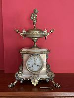 Front view of the complete clock on wooden surface against red background, key in front