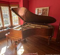 Grand piano with lid open showing interior and carved front leg
