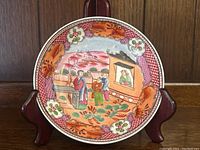 Full view of the antique Japanese ceramic dish with detailed floral borders and central figurative scene.