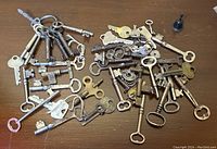 Overview of the assorted antique skeleton keys and modern keys spread on a wooden surface.