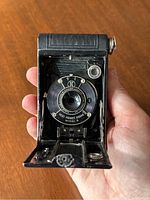 Front fold-out view of the camera showing lens, shutter dials, and black bellows, with bellows stuck and not folding out properly.