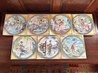 All seven porcelain plates displayed in original boxes