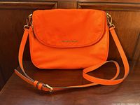 Front view of the orange nylon Michael Kors purse with strap laid out in front