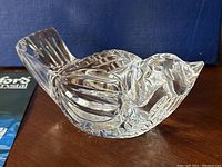 Close-up view of the clear crystal bird figurine showing feather details and cut facets.