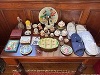 Wide view of vintage and antique trinkets, dishes, small vases, and new slippers arranged on wooden table