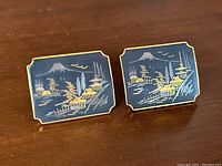 Front view of pair of cufflinks showing the detailed Mount Fuji and village landscape scene in gold, blue and navy hues with gold-tone frame.