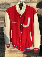 Front view of vintage red and white letterman jacket with embroidered name 'Sandra', chenille 'J' patch, and number 19 on sleeve.
