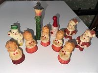 Front view of all 9 holiday candles arranged on white surface.