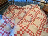Quilt spread out showing overall red and white patchwork design with visible folds and wear.