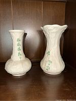 Front view of both Belleek vases side by side showing their shape, texture, and shamrock designs on porcelain.