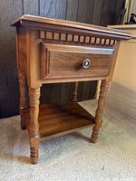Front angled view of end table showing drawer detail, turned legs, and bottom shelf.