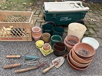 Full view of garden tools, pots, milk crate and rolling cooler stool.