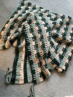 Full view of the folded hand crocheted afghan blanket showing colors and tassels.