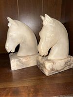 Pair of marble horse head bookends showing the front and side profiles, highlighting the detailed carving and natural marbled base.
