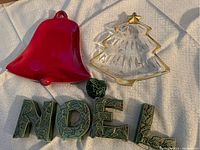 Ceramic NOEL candleholders, small ceramic tree, red bell dish, and glass Christmas tree dish on white surface