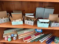 Shelves with a variety of boxes of PartyLite votives, tea lights, red and green taper candles, plus silver and purple metallic spiral taper candles and a jar candle.