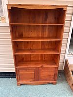 Front view of the solid pine bookcase showing four shelves and sliding doors at bottom.