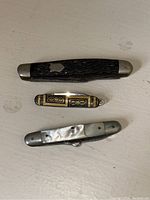Top side view of three pocket cutters showing handles and size comparison with pen