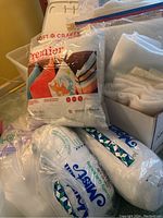 Lot items arranged including large bags of quilt batting and fiberfill, and boxed batting pieces and pillow inserts.
