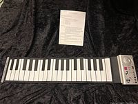 Roll A Piano flexible roll-up toy piano laid out flat showing full keyboard and control panel.