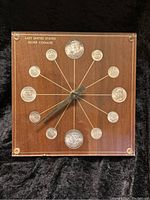 Full frontal image of the clock showing all 12 US silver coins arranged in a circular pattern with gold lines connecting each coin to the center where the clock hands are mounted. Clock face engraved with 'LAST UNITED STATES SILVER COINAGE'. Sequenced coins clearly visible.
