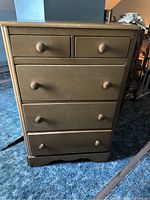 Front view of the dresser showing five drawers with round wooden knobs and signs of surface wear.