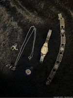 Full lot showing all jewelry pieces and Timex watch on black fabric background.