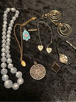 Photo showing entire lot of vintage mixed jewelry pieces on black surface.