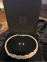Pearl necklace and earrings in the black velvet-lined Avol box with geometric pattern on box lids.