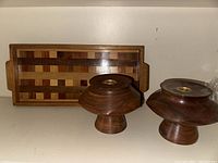 Two solid walnut candlestick holders next to a rectangular multi species wood tray.
