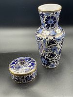 Front and top view of the vase and covered trinket dish showing cobalt and light blue floral and deer patterns with gold outlines on white ceramic.