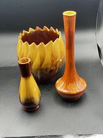 Full view of three pottery pieces: scalloped planter, small vase with tilted neck, and taller rounded base vase.