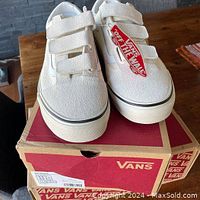 Front view of Vans Old Skool V shoes on top of Vans box, showing velcro straps and Off The Wall tag.