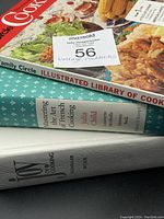 Side view of three hardcover cookbooks stacked, showing titles and authors on spine: Family Circle Illustrated Library of Cooking 1972, Mastering the Art of French Cooking by Julia Child et al, Joy of Cooking 1975 edition.