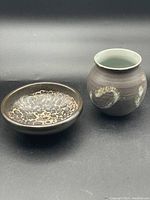 Both pottery pieces side by side on black background showing size and shape differences